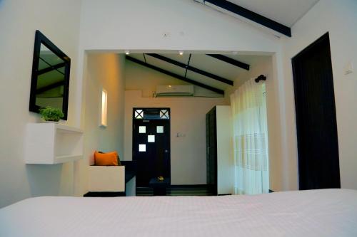 a bedroom with a white bed and a black door at Midigama Holiday Inn in Midigama