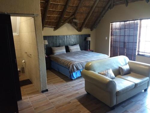 a bedroom with a bed and a couch at Villa Schreiner Guest House in Johannesburg