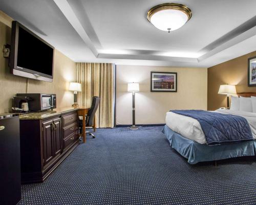 a hotel room with a bed and a desk with a television at Quality Inn Schaumburg - Chicago near the Mall in Schaumburg