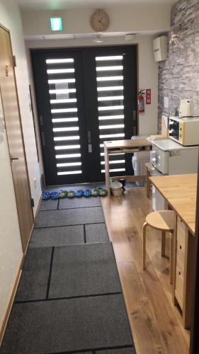 a room with a kitchen with a door and some rugs at Wakatsuki House in Osaka