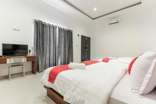 a white bedroom with a bed and a television at RedDoorz Premium @ Setiabudi Medan in Sunggal