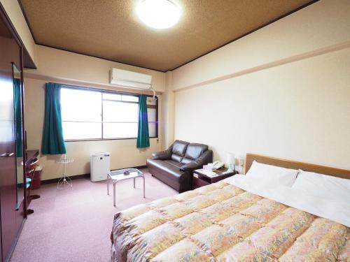 Habitación de hotel con cama y silla de cuero en Sky Heart Hotel Shimonoseki, en Shimonoseki