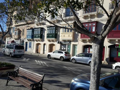 a bench on the side of a street with parked cars at Seafront Room in Msida