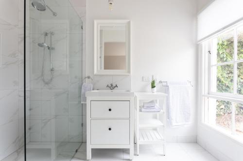a white bathroom with a sink and a shower at A Cottage In Richmond in Richmond