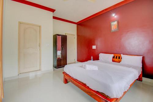 a bedroom with a large bed with a red wall at Holidayincoorg Orchid Villa in Madikeri