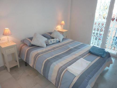 ein Schlafzimmer mit einem Bett mit einer gestreiften Decke und einem Fenster in der Unterkunft Casa Irma in Nerja
