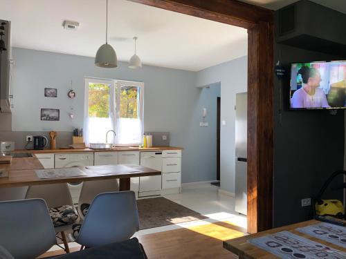 a kitchen with a table and a tv on the wall at Ostoja Kaczórki in Kaczórki