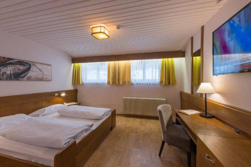 a bedroom with a bed and a desk and a tv at Hotel Mondschein in Sesto