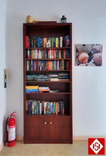 a book shelf filled with books next to a wall at Semiramis Guesthouse in Adamas