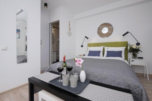 Schlafzimmer mit einem Bett und einem Tablett mit Weingläsern in der Unterkunft Apartamenty Via Mare in Ustka