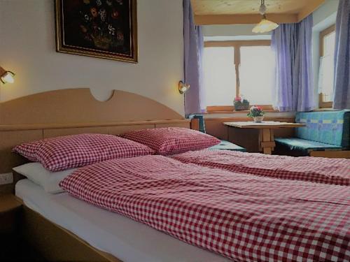 una camera con due letti con lenzuola a quadri rosse e bianche di Zimmer - Hinterwalderhof a Mühlbach