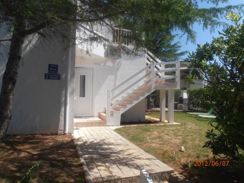 a white house with a staircase in a yard at Apartments Febsis in Novalja
