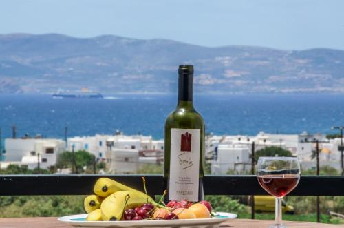 a bottle of wine sitting next to a plate of fruit at Orama Apartments in Agia Anna Naxos