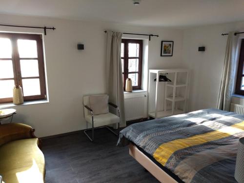 a bedroom with a bed and a chair and windows at Forester in Malmedy