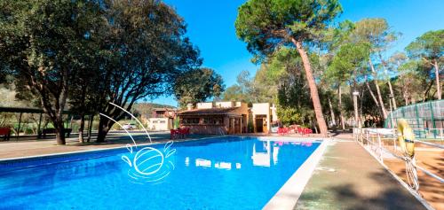 a large blue swimming pool with a house in the background at Camping Esponellà in Esponellá