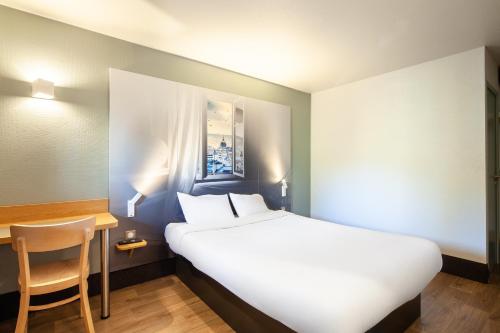 B&B HOTEL Pontault Combault في بونتولت-كومْبو: سرير في غرفة مع مكتب وسرير سيد
