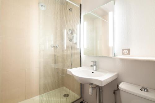 a bathroom with a sink and a shower with a mirror at B&B HOTEL Pontault Combault in Pontault-Combault