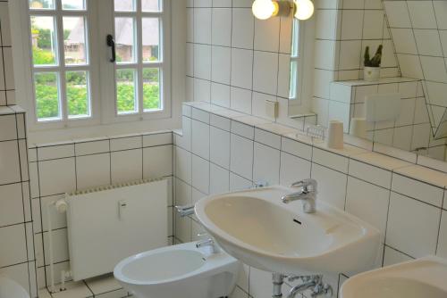 uma casa de banho branca com um lavatório e um espelho em Schlottmann em Keitum