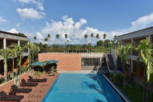 a large swimming pool with chairs and a building at Sansuntree in Lamphun