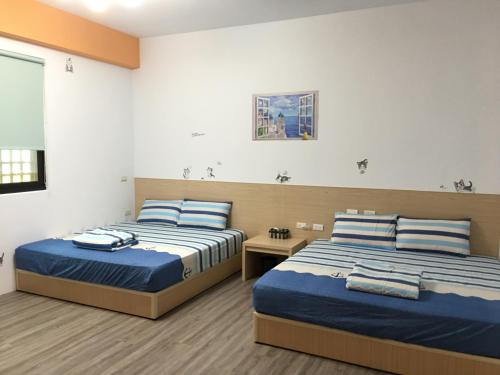 two beds in a bedroom with blue and white sheets at Meow Meow Fish B&B in Baisha