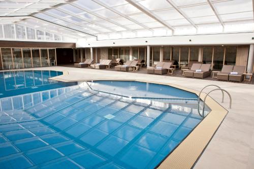 uma grande piscina num edifício com cadeiras em WestCord Strandhotel Seeduyn em Oost-Vlieland
