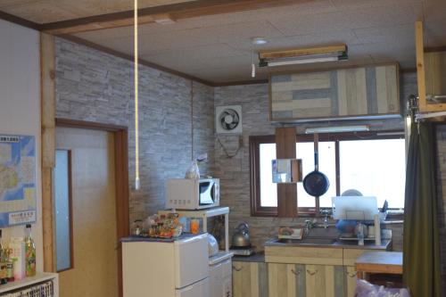 a kitchen with a refrigerator and a microwave at Shoei backpackes hostel in Teshikaga