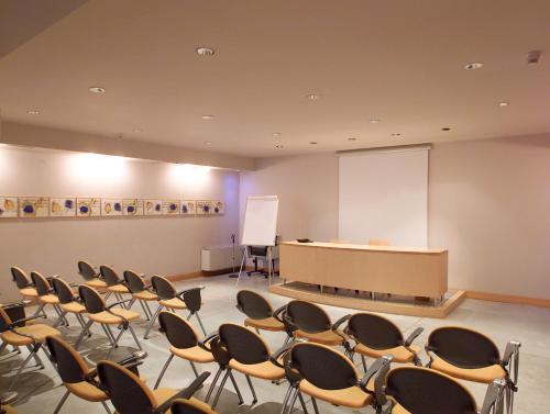 a lecture room with chairs and a podium and a screen at Hotel Aleramo in Asti