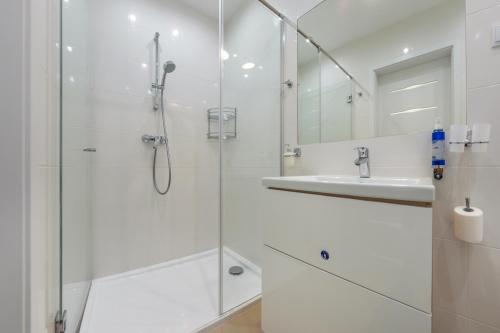 a white bathroom with a shower and a sink at Dwie Sosny z sauną, Sun & Snow in Ustronie Morskie