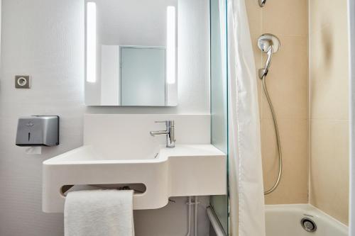 a white bathroom with a sink and a shower at B&B HOTEL CAEN Sud in Ifs