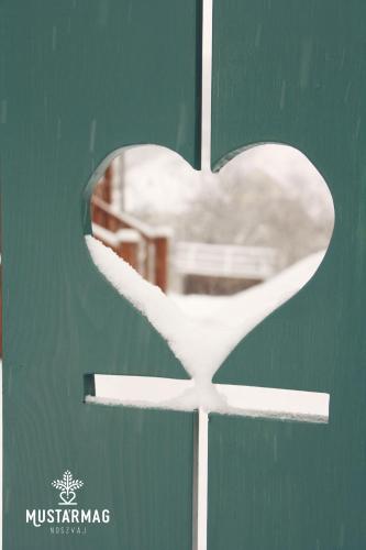 a white heart on a green door with a window at Mustármag Vendégház in Noszvaj