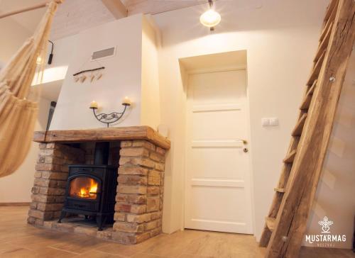 a living room with a brick fireplace and a door at Mustármag Vendégház in Noszvaj