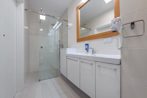 a bathroom with a shower and a sink and a mirror at Dwie Sosny z sauną, Sun & Snow in Ustronie Morskie