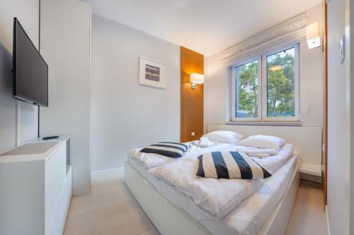 a white bedroom with a bed and a window at Dwie Sosny z sauną, Sun & Snow in Ustronie Morskie