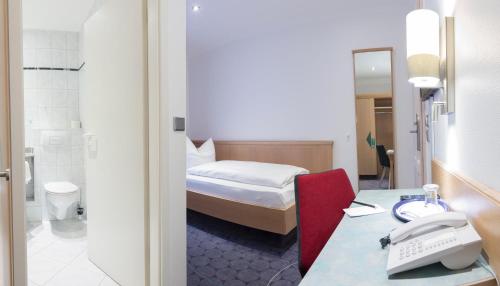 ein Hotelzimmer mit einem Bett und einem Schreibtisch mit einem Telefon in der Unterkunft Hotel Weißes Roß in Elsterwerda