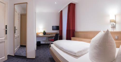 ElsterwerdaにあるHotel Weißes Roßのベッドとデスクが備わるホテルルームです。