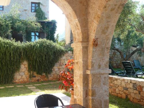 a stone archway with chairs and a stone wall at Maison Viros in Kardamyli