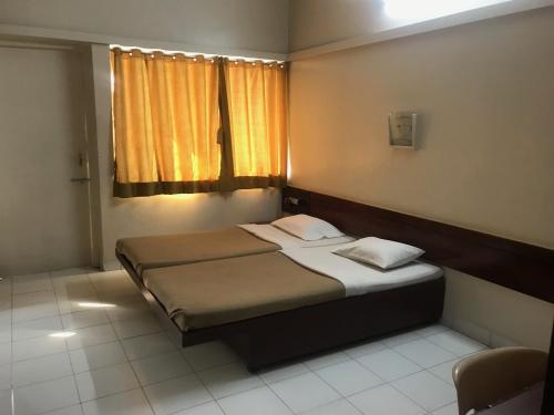 um pequeno quarto com uma cama e uma janela em Maurya Residency em Pune