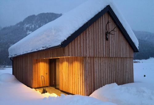 een klein houten gebouw met sneeuw op het dak bij dasGams in Gosau