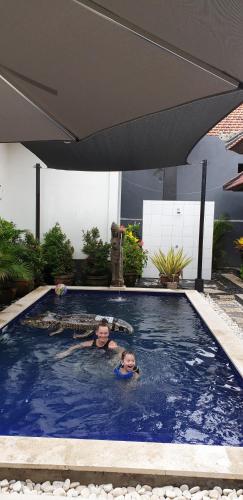 two people swimming in a pool with an umbrella at Villa Jackson in Tejakula