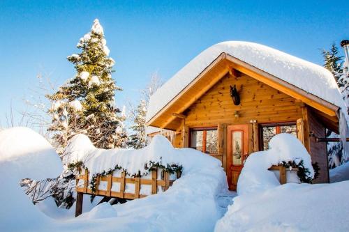 a log cabin covered in snow next to a christmas tree at Kedra Village in Kédra