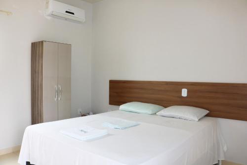 a bedroom with a white bed with a wooden headboard at Pousada Sol Nascente in Piranhas