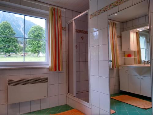 ein Bad mit einer Dusche, einem Waschbecken und einem Fenster in der Unterkunft Ferienhaus Karin in Ramsau am Dachstein