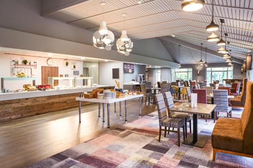 a restaurant with tables and chairs and a counter at Novotel Manchester West in Worsley