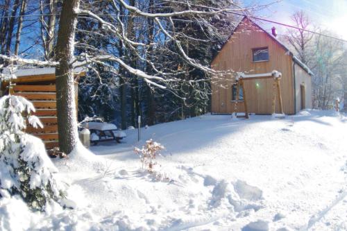 a cabin in the snow with a bench in front at Chata na sjezdovce in Malenovice