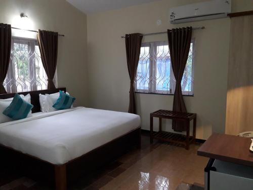 a bedroom with a large bed and two windows at Rudraksha Holiday Homes in Candolim