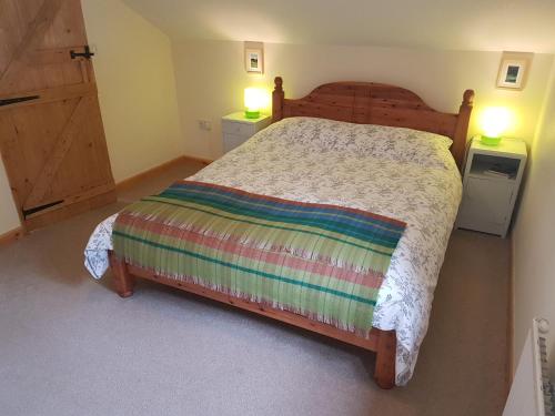 a bedroom with a wooden bed with two lights on at Seren Loft - Cynghordy, Llandovery in Llandovery