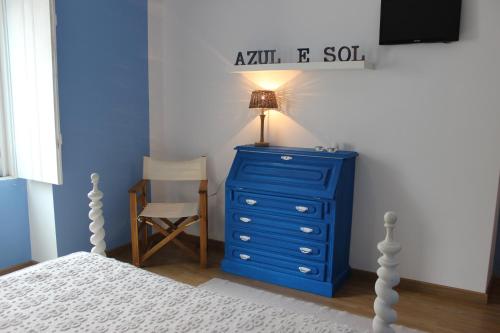 a blue dresser with a lamp and a chair in a bedroom at Segredo d'Alecrim in Fronteira