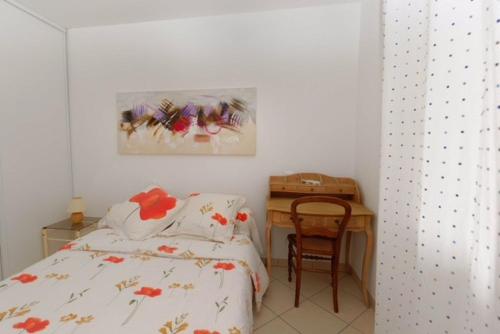 een slaapkamer met een bed en een bureau met een schilderij bij Résidence les Eucalyptus in LʼÎle-Rousse