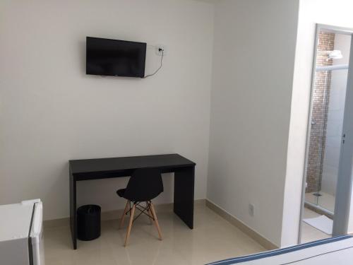 a black desk with a chair and a television on a wall at JP Palace Hotel in Saquarema