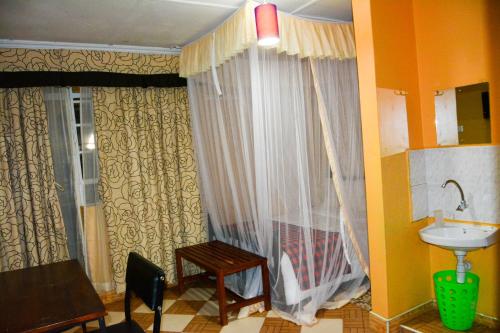 a bathroom with a sink and a window with curtains at Pine Breeze Getaway Lukenya in Athi River
